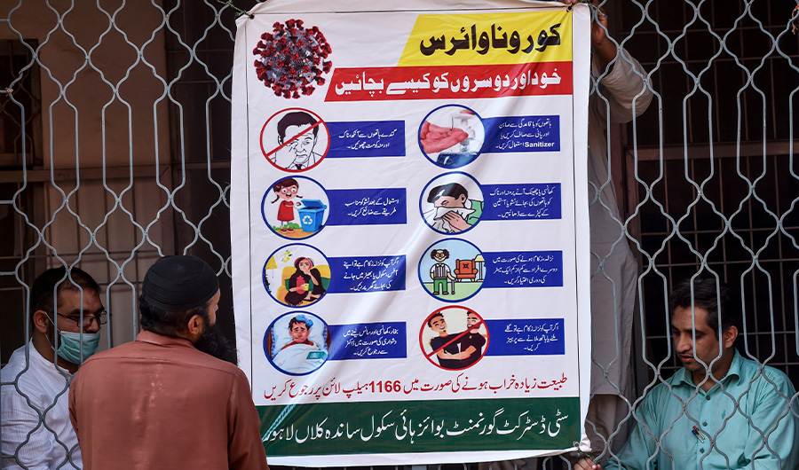 School workers hang an awareness poster at a school in Lahore on September 12, 2020. (AFP)