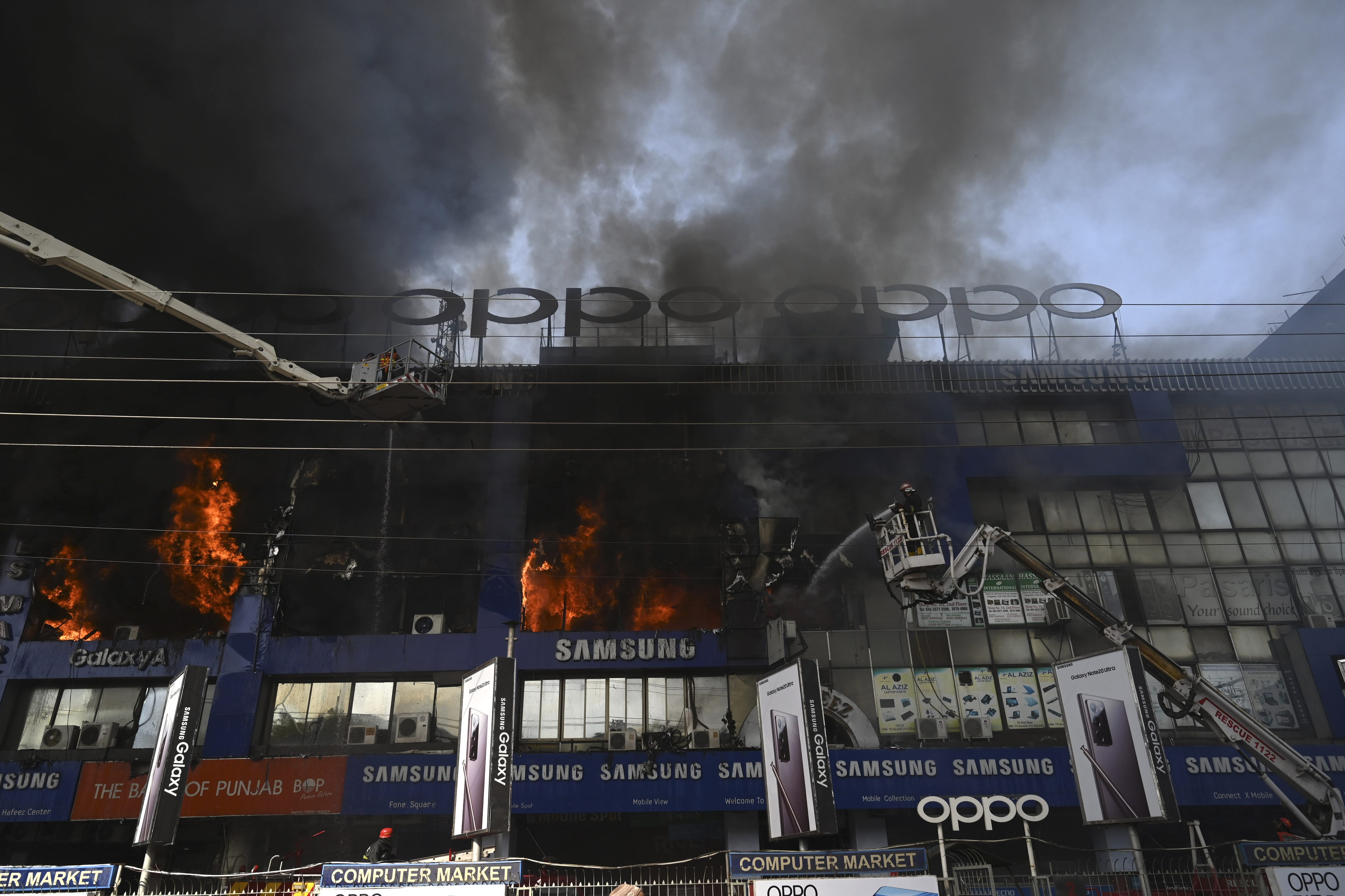 Firefighters try to extinguish a fire that broke out in a four-storey commercial building that houses mobile, laptop and electronics plaza in Lahore on October 18, 2020. (AFP)