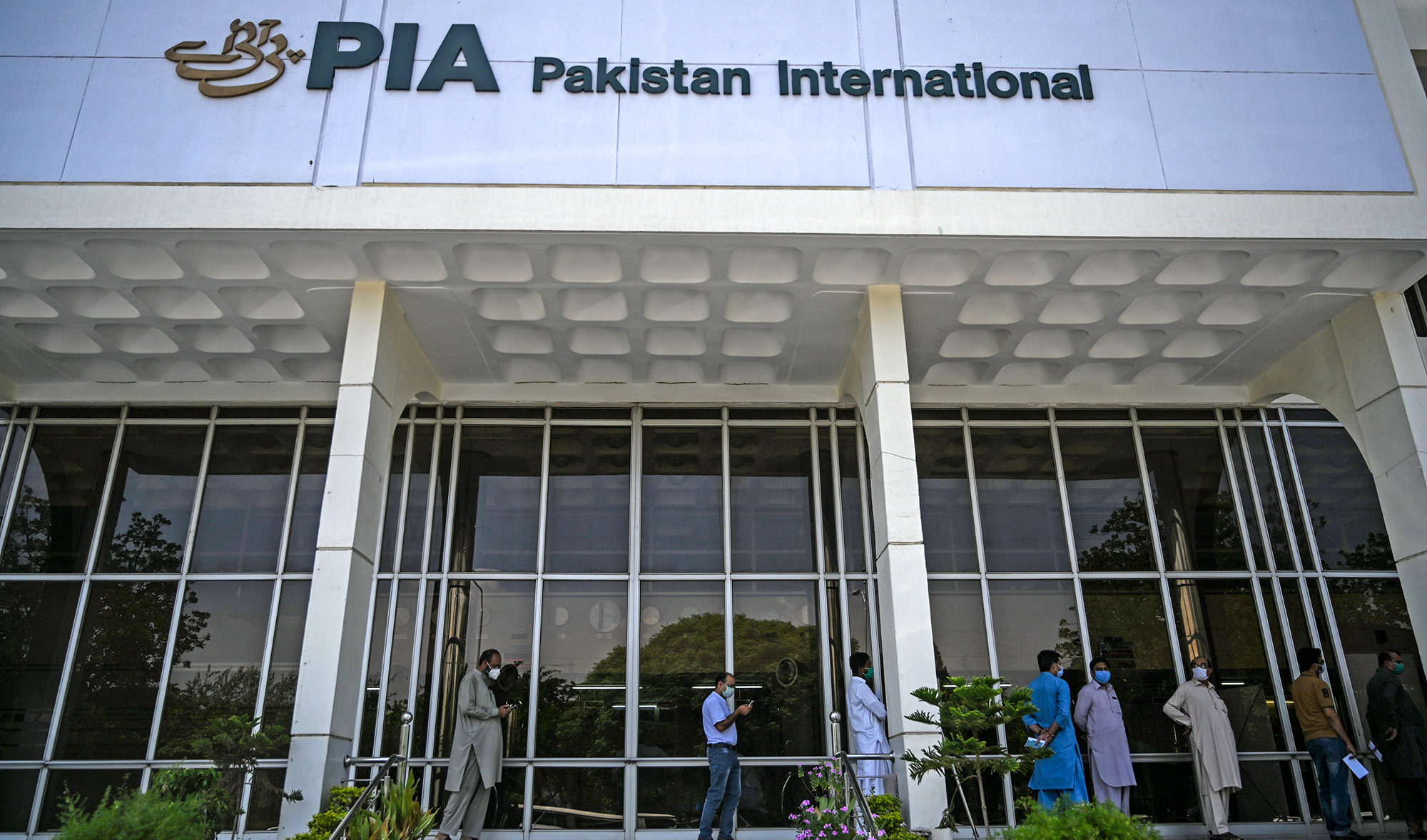 People stand in queue as they wait their turn to buy flight tickets outside Pakistan International Airlines (PIA) office in Islamabad on July 1, 2020. (AFP/File)
