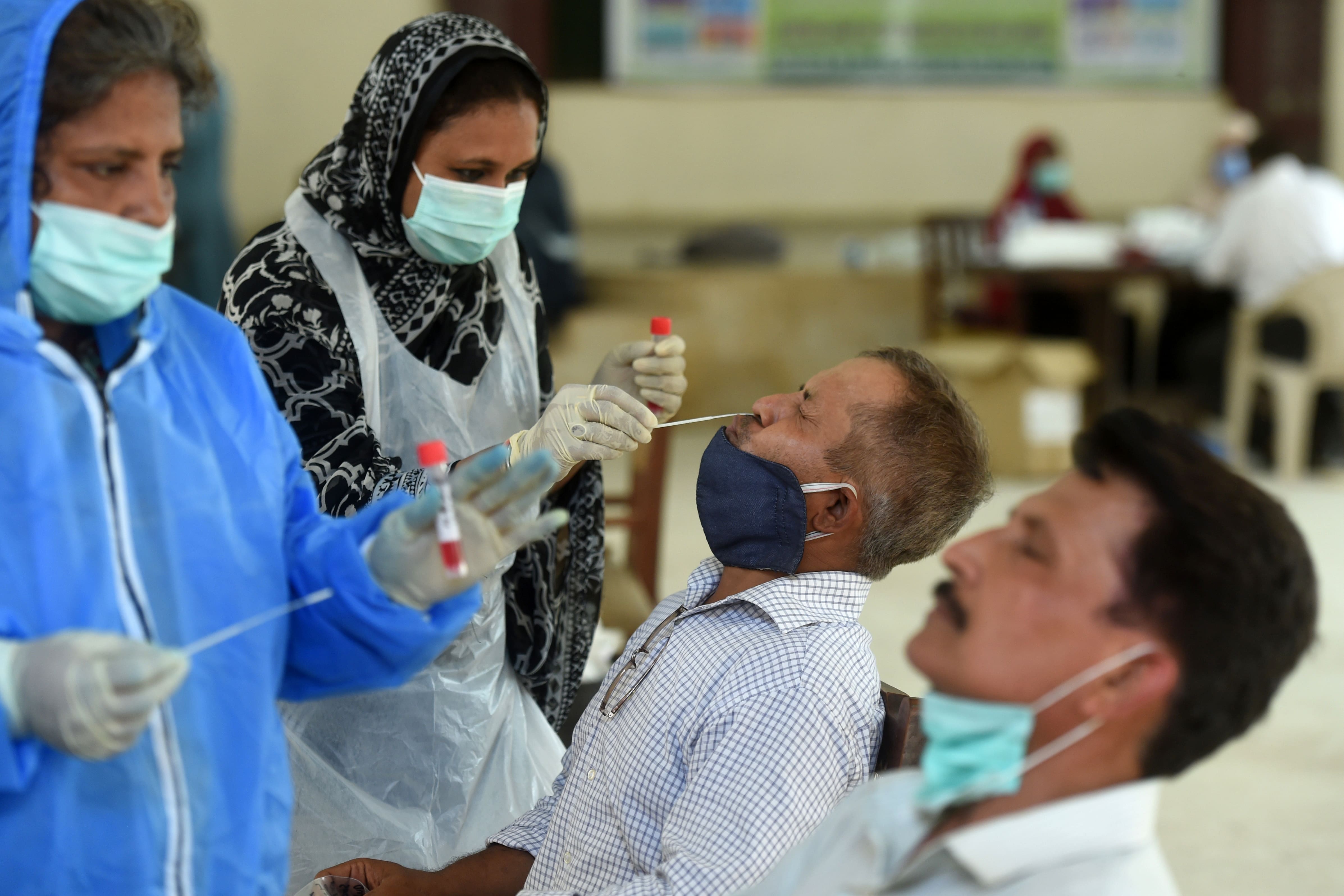 Health official collect swab samples from teachers to test for the COVID-19 coronavirus at a government school following the government's announcement to reopen educational institutes starting from September 15, in Karachi on September 14, 2020. (AFP)