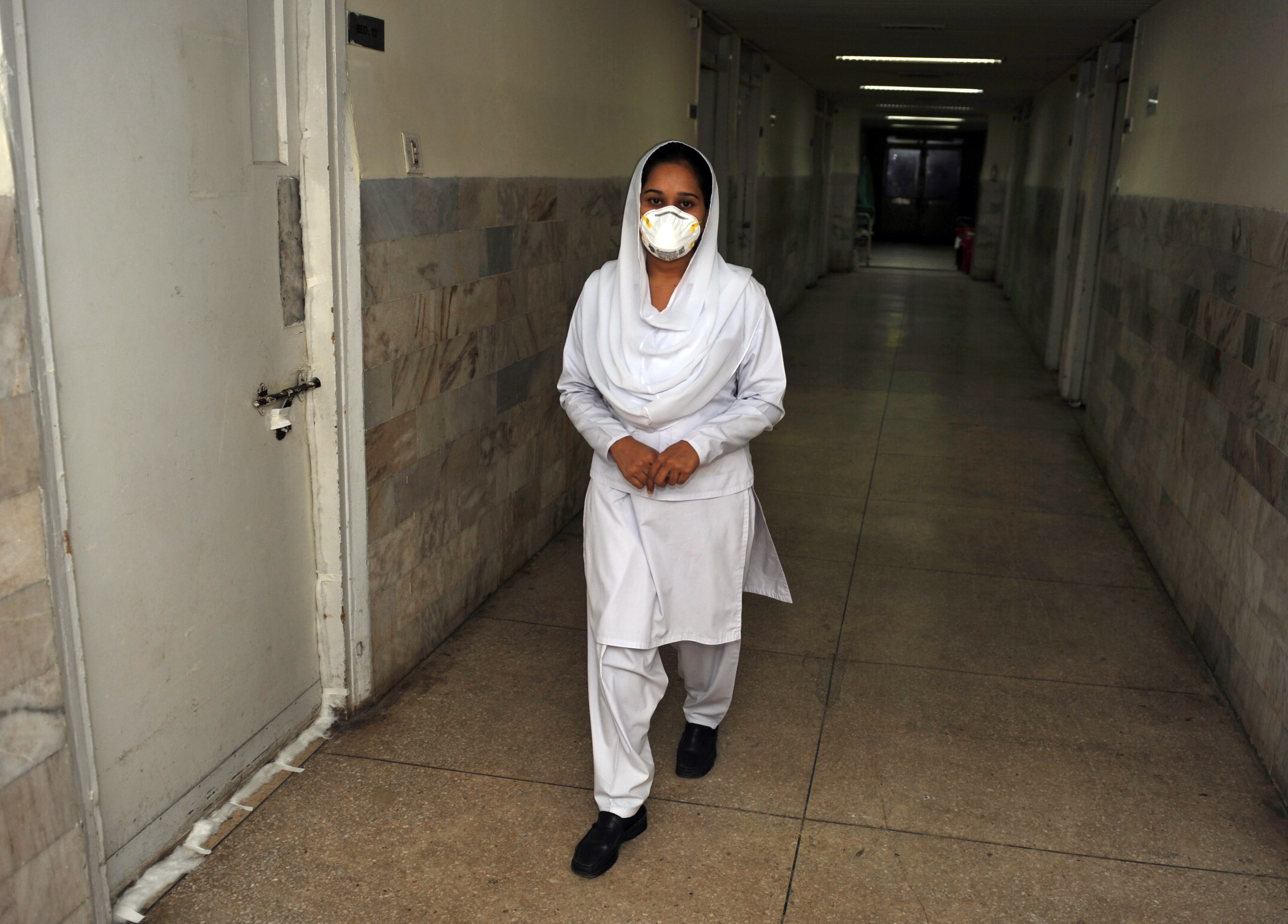 A Pakistani paramedic leaves a room with swine flu patients at the Pakistan Institute of Medical Sciences (PIMS) in Islamabad on September 25, 2009. (AFP)