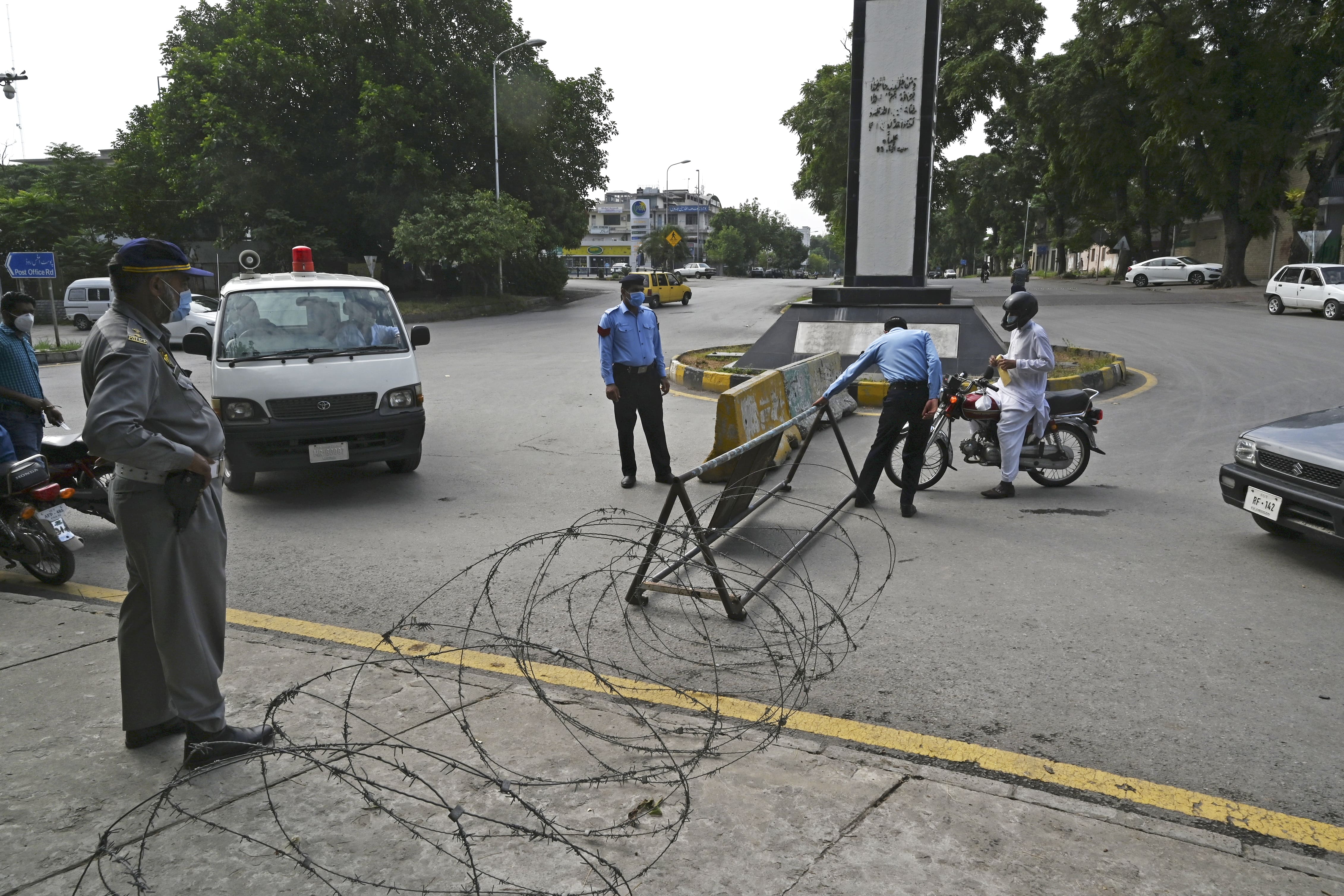 Police officers wearing facemasks stand beside motorists next to a street sealed by the authorities at a residential area in Islamabad on June 25, 2020 as COVID-19 coronavirus cases continue to rise. (AFP)