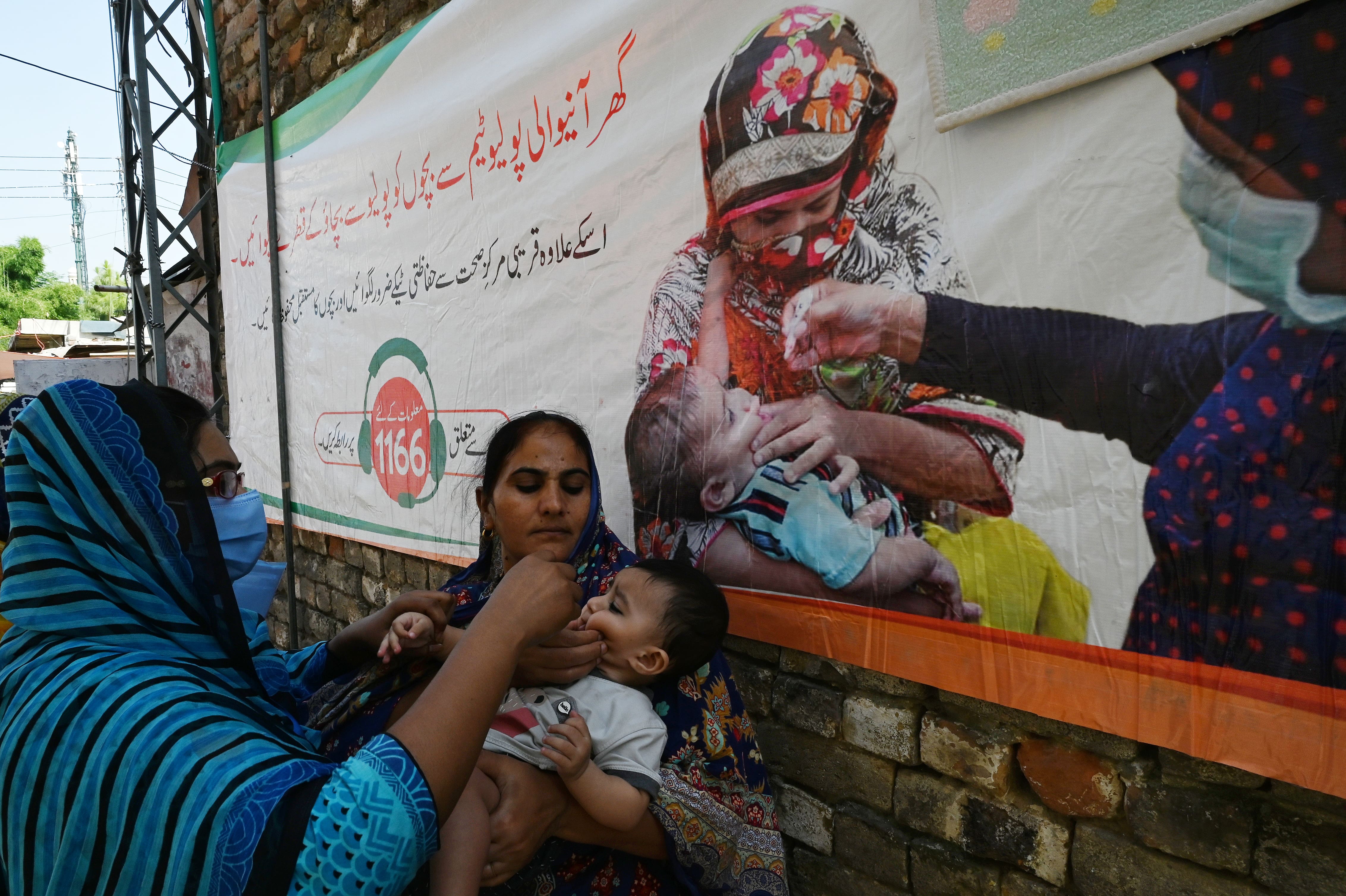 A health worker (L) administers polio vaccine drops to a child during a polio vaccination door-to-door campaign at a low-income residential area in Islamabad on September 21, 2020. (AFP)