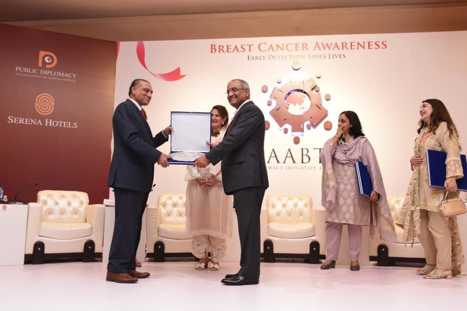 A rare male breast cancer survivor turned cancer awareness activist, Aizaz Ahmed Chaudhary, receives a shield from CEO Serena hotels Aziz Boolani in recognition of his services on October 13, 2020. (Photo courtesy: Serena Hotel)