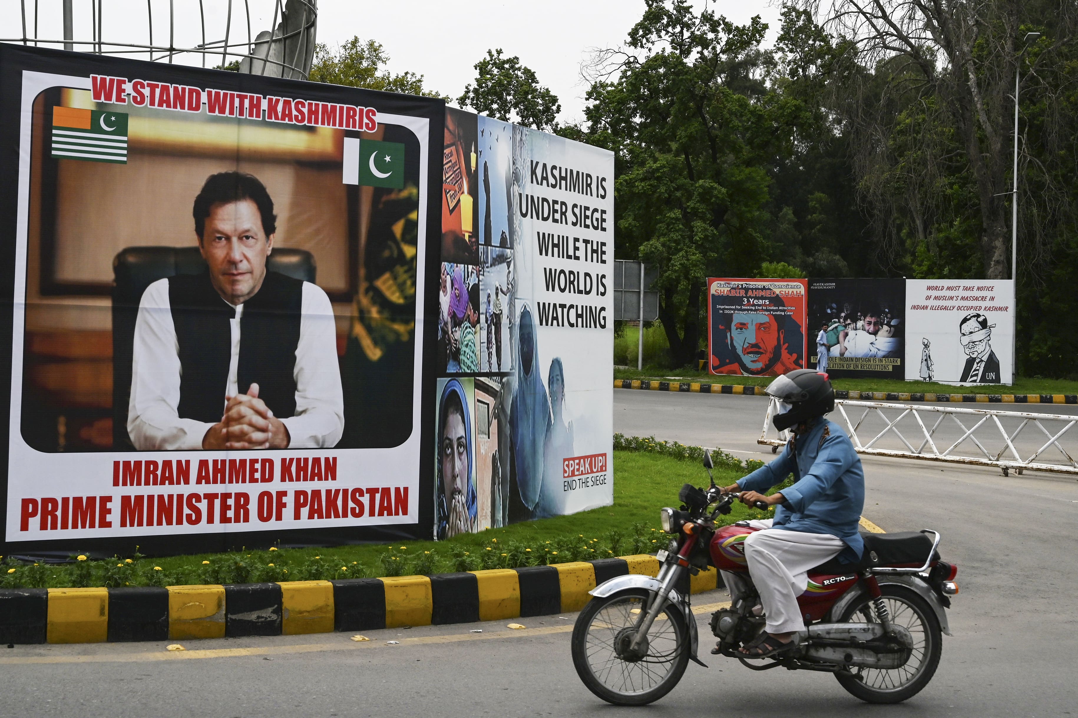 A motorcyclist rides past a billboard displaying a picture of Pakistan's Prime Minister Imran Khan along a street in Islamabad on August 4, 2020 ahead of the Yaum-i-Istehsal or Day of Exploitation on August 5, on the first anniversary after India scrapped Muslim-majority region Kashmir's semi-autonomous status and imposed a major security clampdown. (AFP)