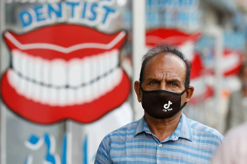 A man wears a protective face mask with the TikTok logo as he walks along dental shops in Karachi, Pakistan July 14, 2020. (REUTERS)
