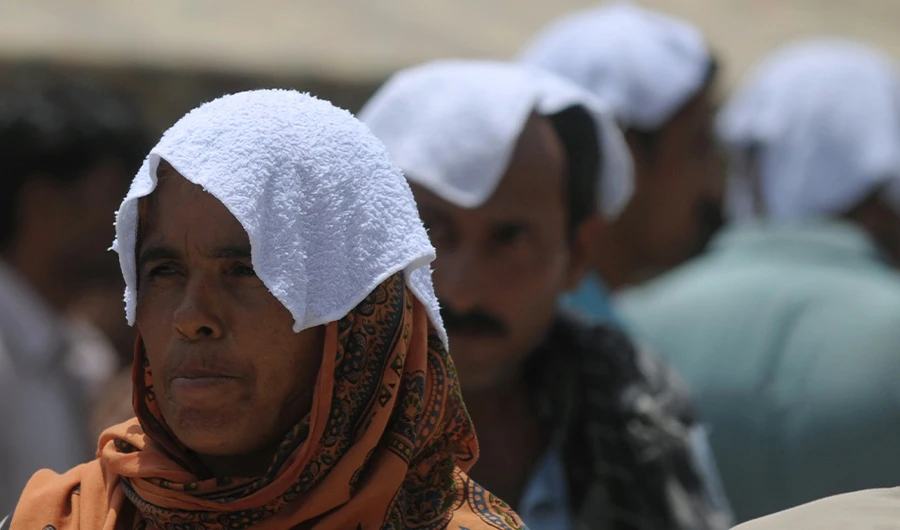 FILE: Pakistani relatives of heatstroke victims, their heads covered with wet towels, wait outside a hospital during a heatwave in Karachi on June 29, 2015. (AFP)