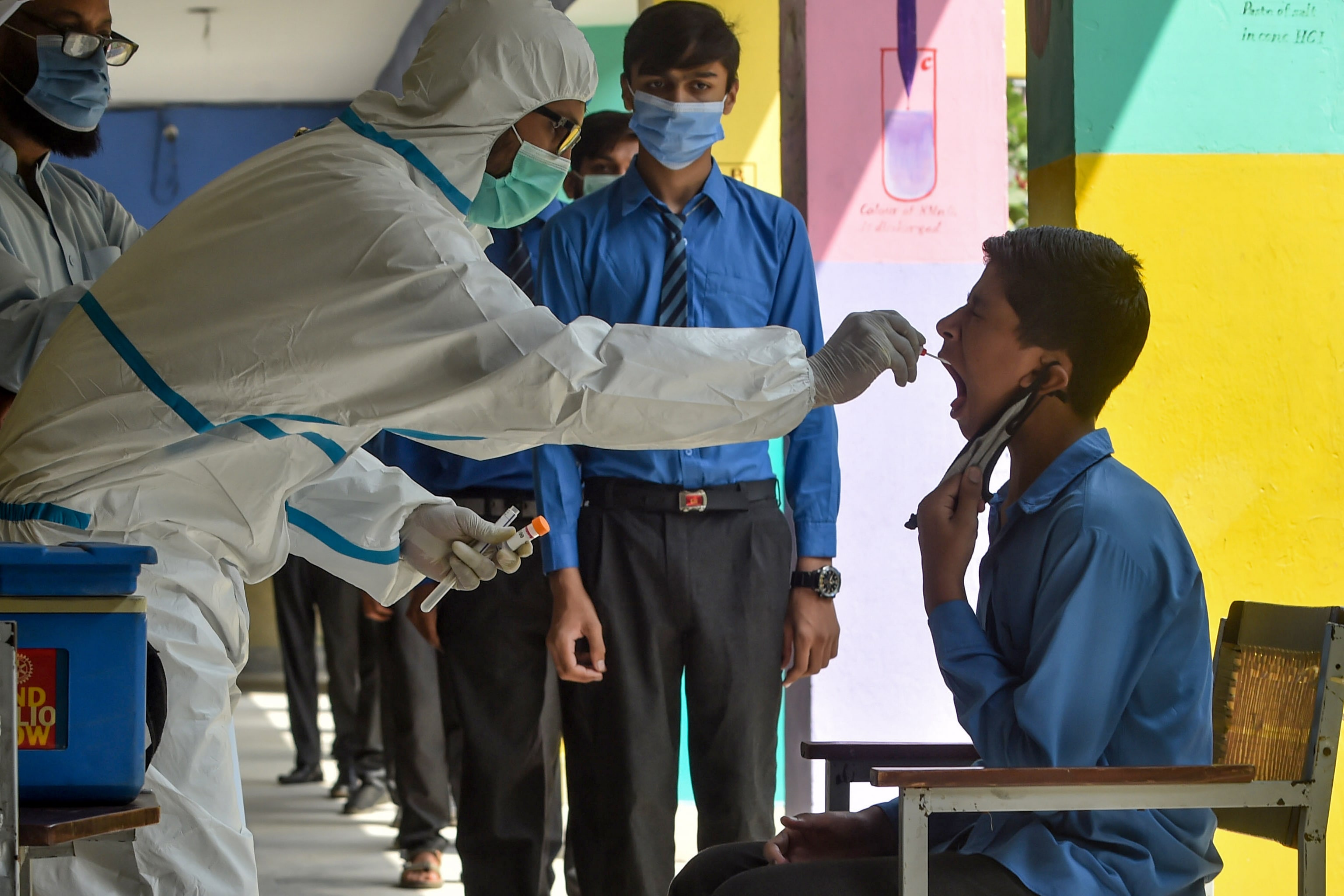 A health official (L) collects a swab sample from a student to test for the Covid-19 coronavirus at a government school in Lahore on October 1, 2020, after the educational institutes reopened nearly six months after the spread of the Covid-19 coronavirus. (AFP)