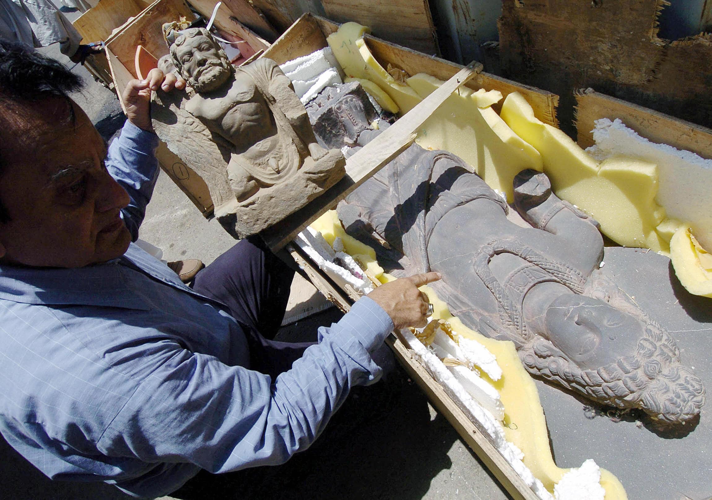 A Pakistani customs worker examines seized antiques at the sea port in Karachi, 23 June 2005. (AFP)