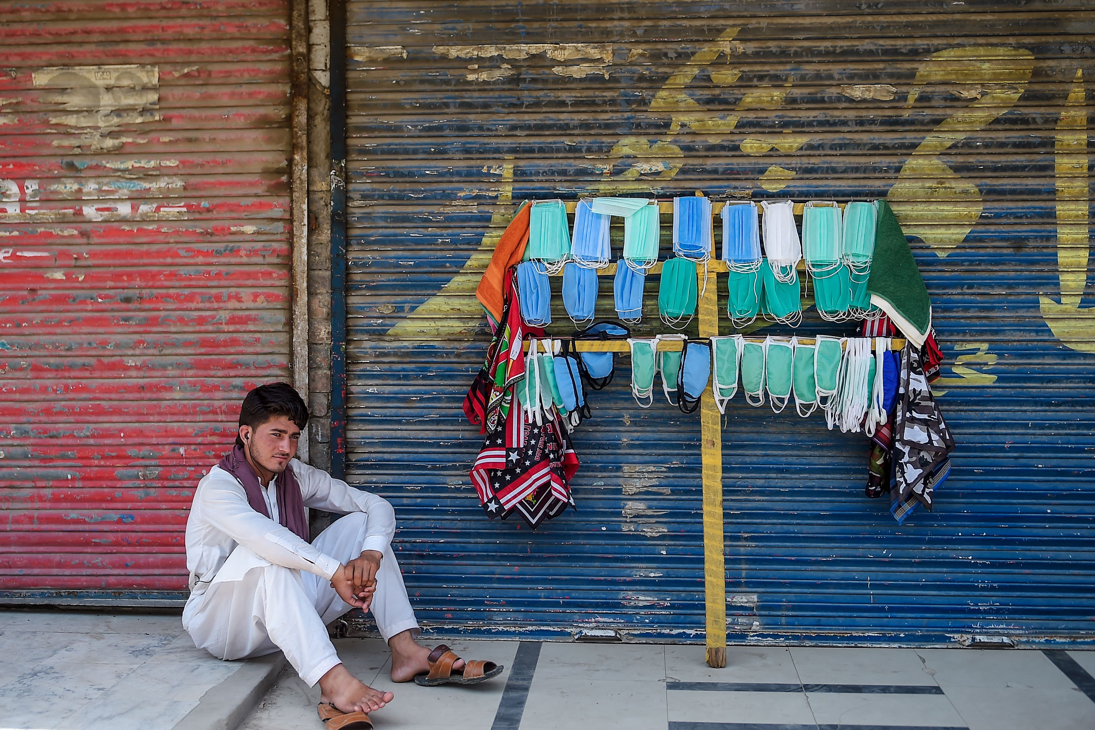 A street vendor selling facemasks sits as he waits for customers on a street in Rawalpindi on July 5, 2020. (AFP)