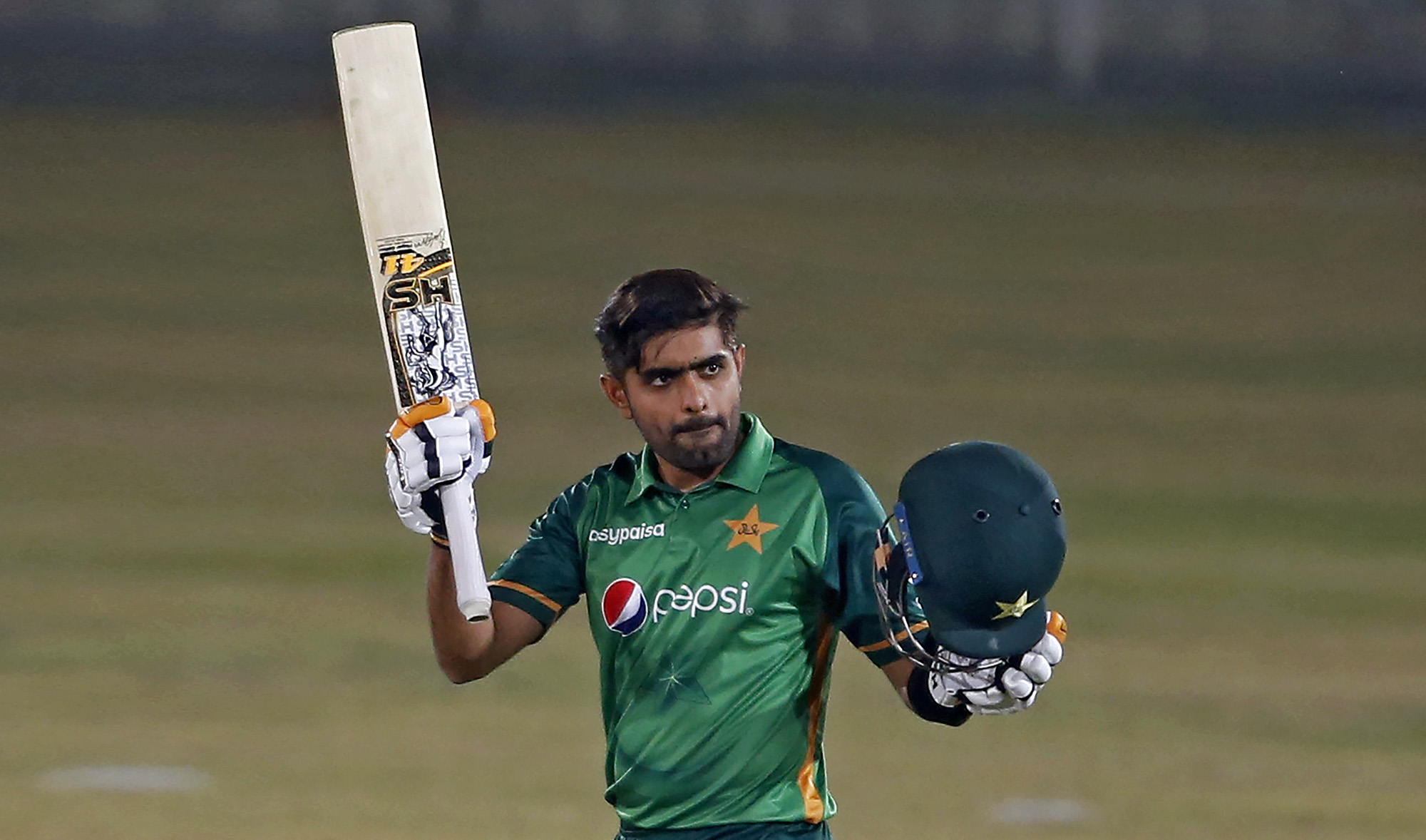 Pakistani batsman Babar Azam raises his bat and helmet to celebrate his century during the 3rd one-day international cricket match against Zimbabwe at the Pindi Cricket Stadium, in Rawalpindi on Nov. 3, 2020. (AP)