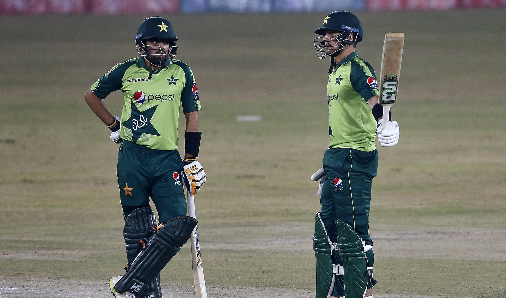 Pakistani batsman Haider Ali, right, raises bat to celebrate his fifty while teammate Babar Azam watches during the 2nd Twenty20 cricket match against Zimbabwe at the Pindi Cricket Stadium, in Rawalpindi on Nov. 8, 2020. (AP)
