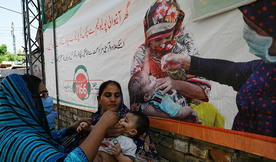 A health worker (L) administers polio vaccine drops to a child during a polio vaccination door-to-door campaign at a low-income residential area in Islamabad on September 21, 2020. (AFP)