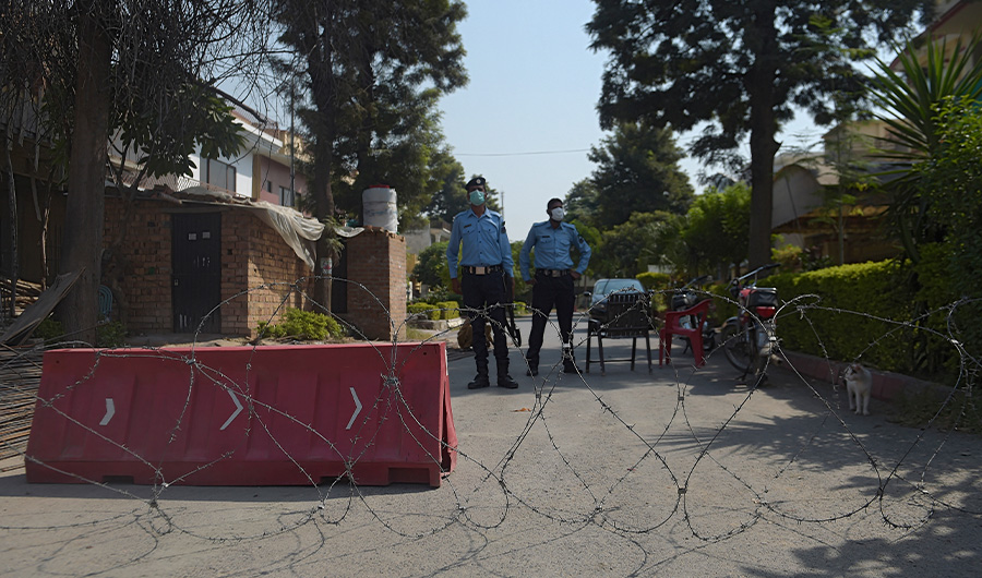 Pakistani policemen wearing facemasks stand guard in front of a cordoned off area after some residents tested positive for Covid-19 coronavirus, in Islamabad on October 11, 2020. (AFP)