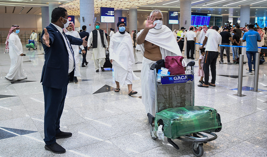 Mask-clad Pakistani travellers arriving to Saudi Arabia to perform the year-round Umrah pilgrimage, walk with their luggage at King Abdulaziz International Airport in the Red Sea coastal city of Jeddah on November 30, 2020, before being sequestered for three days as a COVID-19 coronavirus pandemic precaution. (AFP)