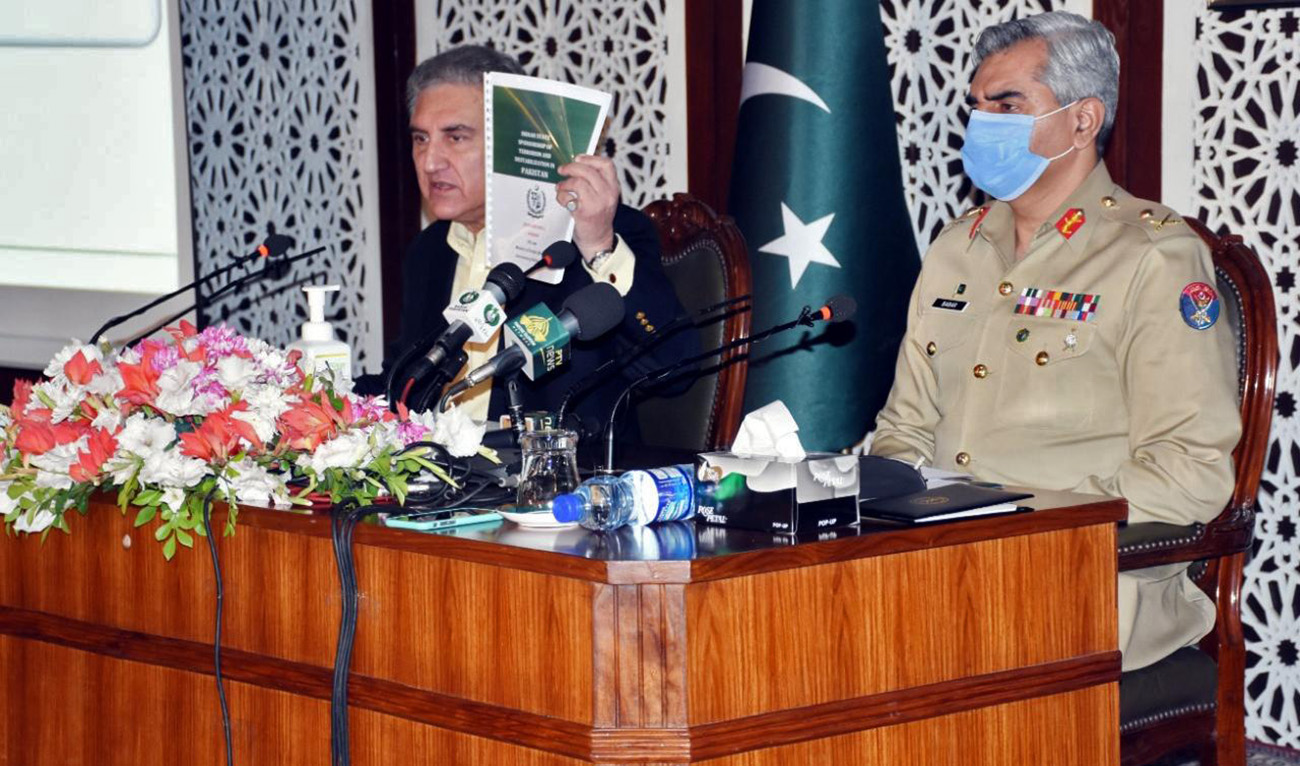 Pakistan's Foreign Minister Shah Mahmood Qureshi displays a dossier containing "irrefutable evidence" of Indian terror while addressing a news conference in Islamabad on November 14, 2020. He is also accompanied by Director General Inter-Services Public Relations Major General Babar Iftikhar. (AN Photo)