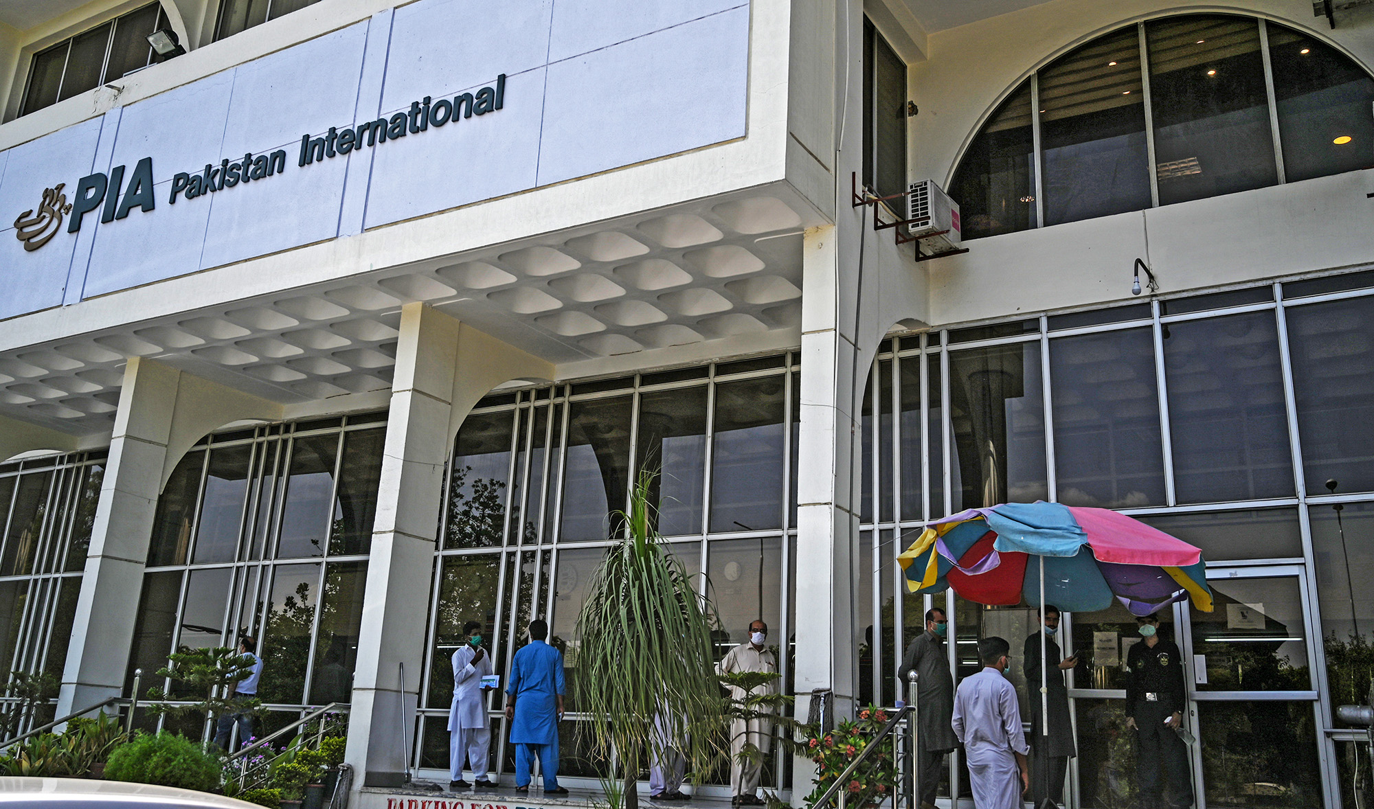 People stand in queue as they wait their turn to buy flight tickets outside Pakistan International Airlines (PIA) office in Islamabad on July 1, 2020. (AFP/File)