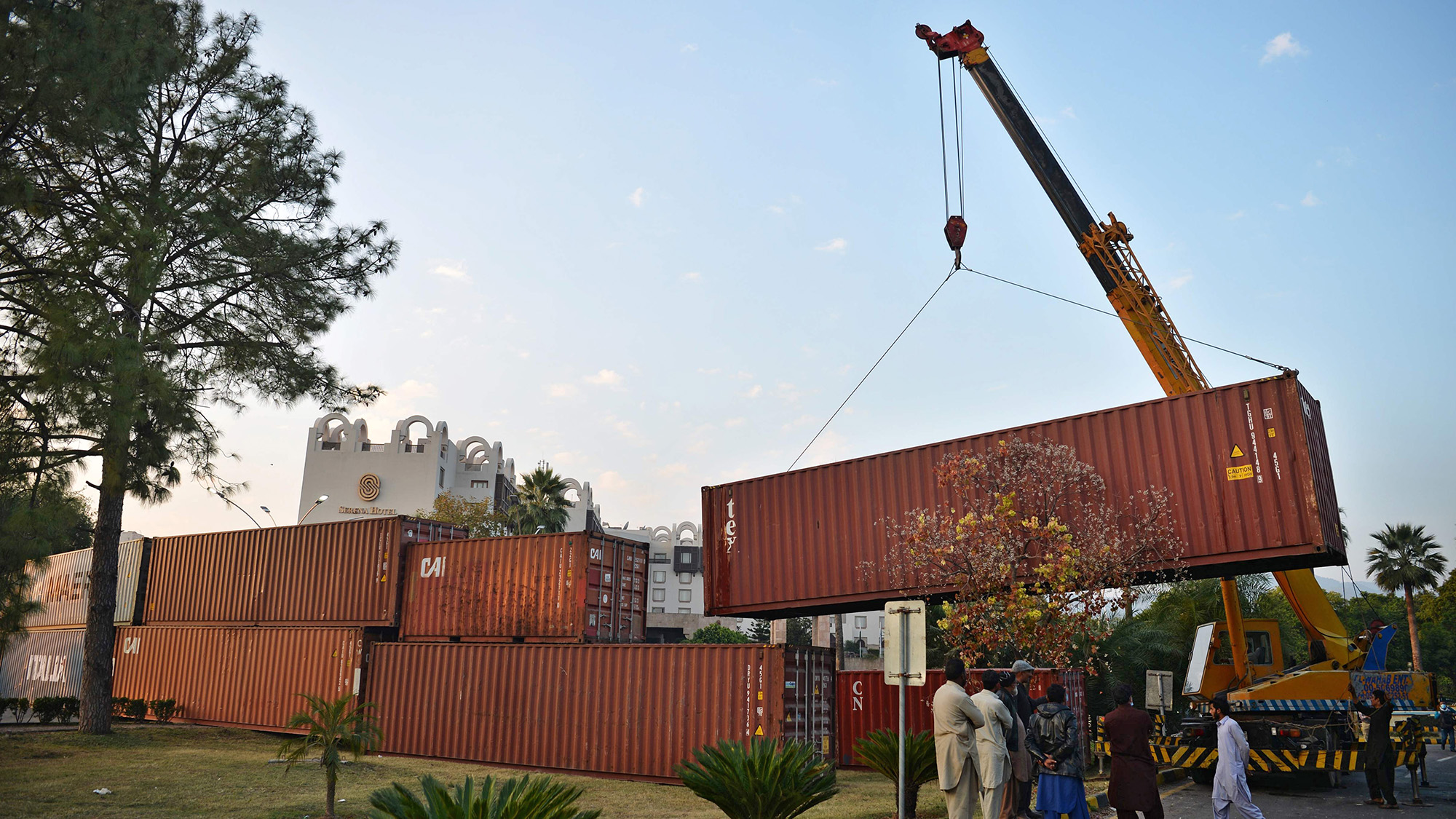Truck drivers stand as workers remove a shipping container in front of the French consulate at the end of an anti-France demonstration by religious party Tehreek-e-Labbaik Pakistan (TLP), in Islamabad on Nov. 17, 2020. (AFP/File)