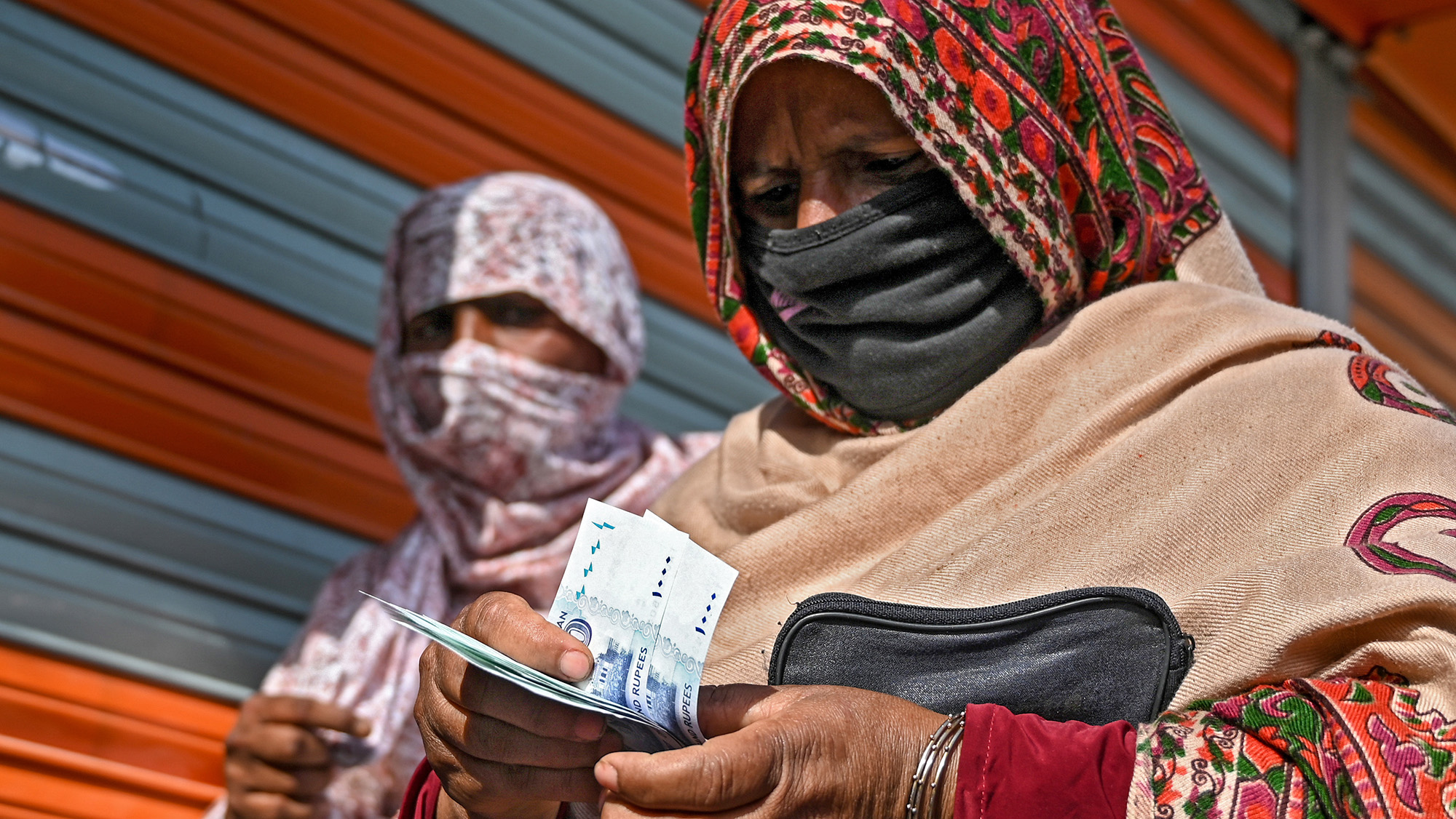 A woman counts rupee notes after collecting cash of financial assistance through a mobile wallet under the governmental Ehsaas Emergency Cash Programme, in Islamabad on April 9, 2020. (AFP/File)