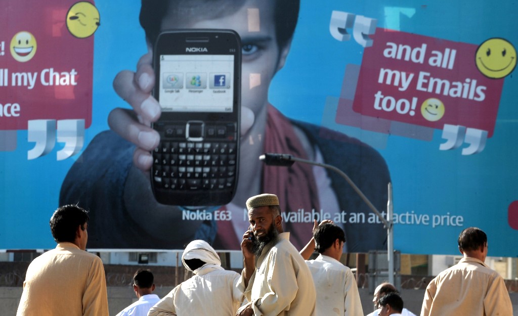 Pakistani pedestrians stand in front of an advertisement for a cellular telephone in Rawalpindi on May 14, 2010. (AFP/File)