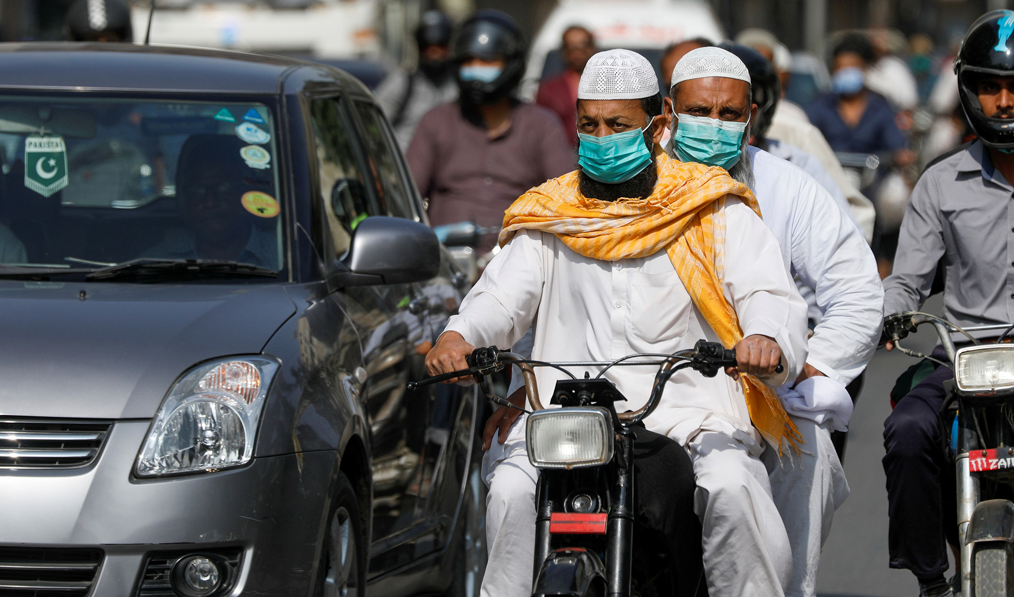 Men wear protective masks as they ride a motorcycle amid the outbreak of the coronavirus disease (COVID-19) in Karachi on Nov. 16, 2020. (REUTERS)