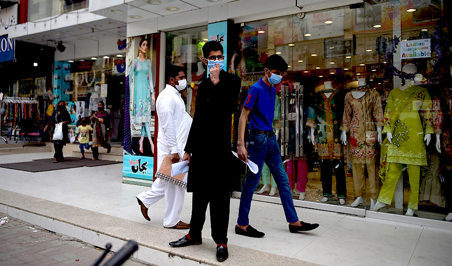People wearing facemasks walk in front of a shopping mall in Rawalpindi on July 28, 2020. (AFP)