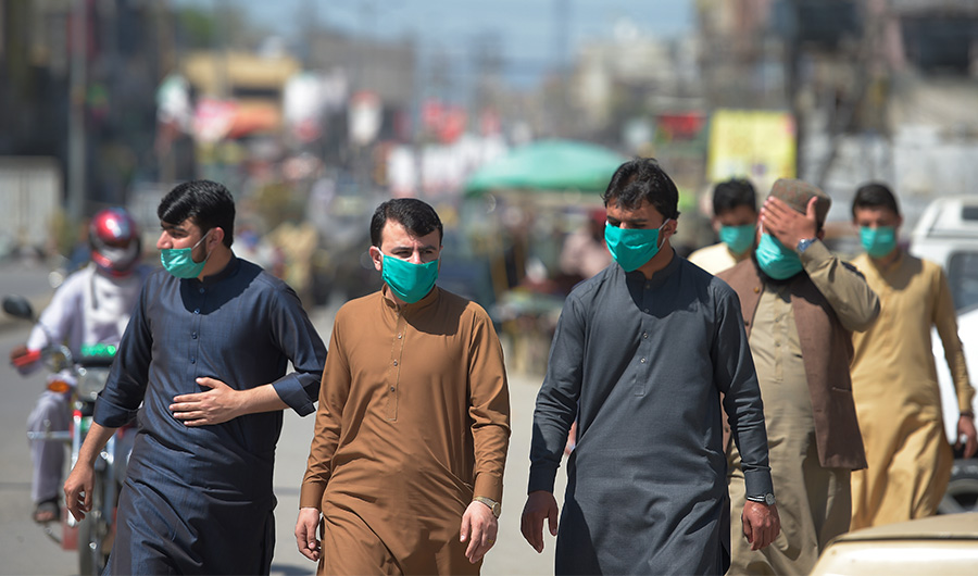 People wearing facemask walks along a road of a closed market area in Rawalpindi on March 22, 2020. (AFP)