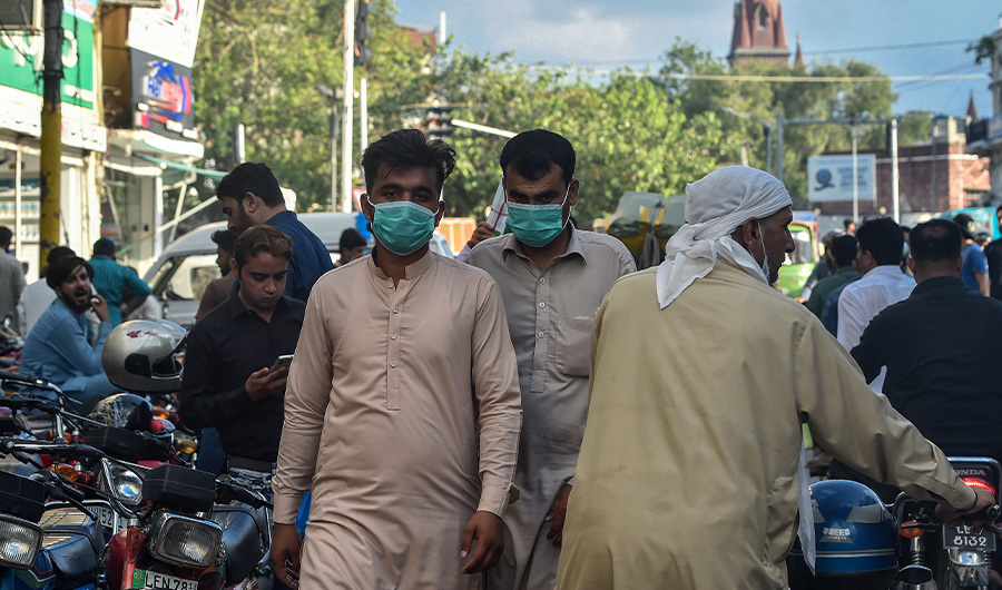 In this picture taken on August 31, 2020, men wearing facemasks as a preventive measure against the Covid-19 coronavirus walk through a market in Lahore. (AFP)