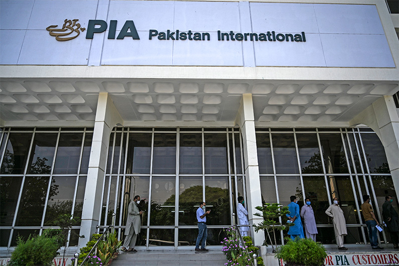 People stand in queue as they wait their turn to buy flight tickets outside Pakistan International Airlines (PIA) office in Islamabad on July 1, 2020. (AFP)