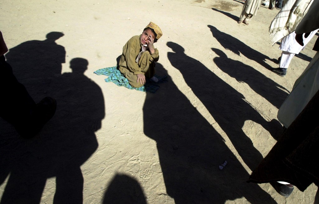 An Afghan child at a madrasa sits among shadows cast by other students who try to prevent journalists from taking pictures, in Quetta on November 12, 2001. (AFP/File)