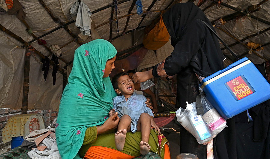 A health worker (R) administers polio vaccine drops to a child during a polio vaccination door-to-door campaign in Lahore on August 16, 2020. (AFP)