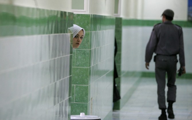 In this 2006 file photo, an Iranian inmate peers from behind a wall as a guard walks by at the female section of the infamous Evin jail. (AFP)