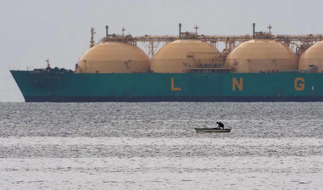 A fisherman stands in his boat as a liquid natural gas tanker (LNG) passes the coast near Havana on June 28, 2009. (REUTERS/File)