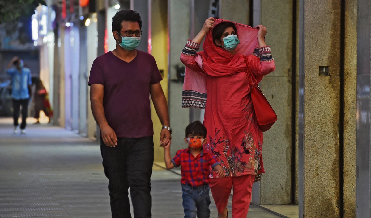 A family wearing facemasks as a preventive measure against the Covid-19 coronavirus walk along side a street, in Karachi on Oct. 29, 2020. (AFP/File)