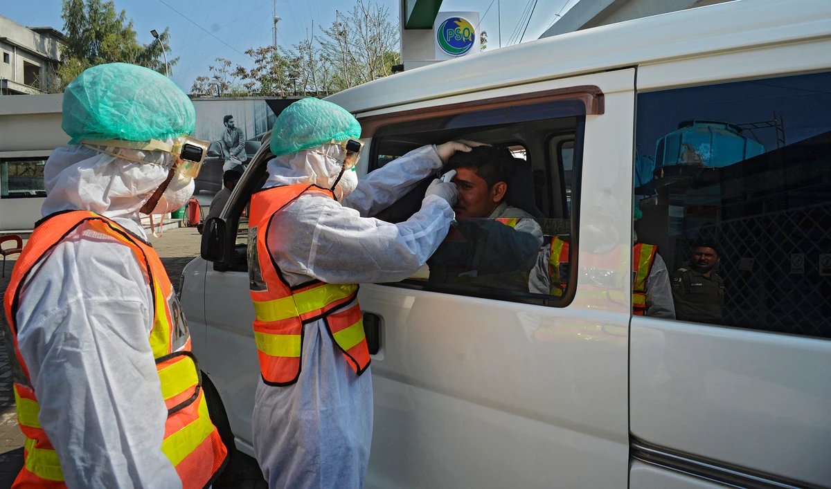 A Pakistani rescue personnel checks the body temperature of a man during a drill exercise as a preventive measure for the spread of the of COVID-19 coronavirus, in Peshawar on March 1, 2020. (AFP/File)