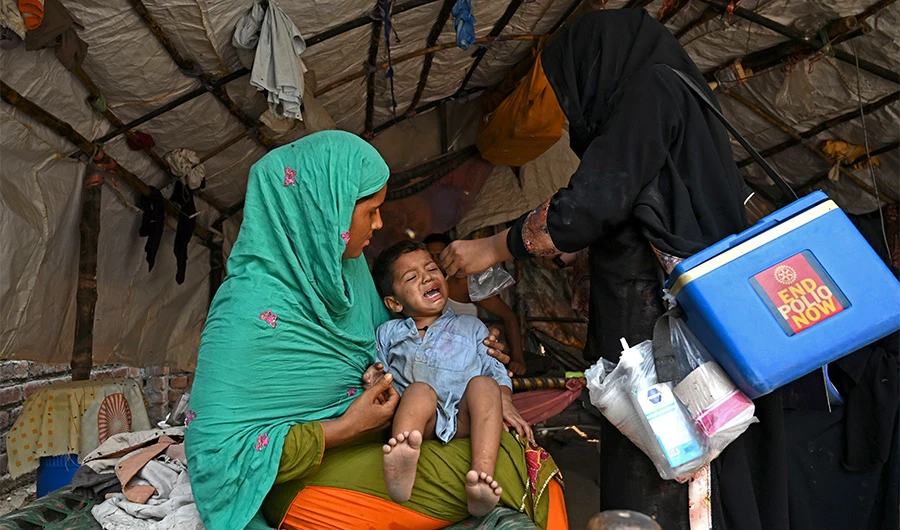 A health worker (R) administers polio vaccine drops to a child during a polio vaccination door-to-door campaign in Lahore on August 16, 2020. (AFP)