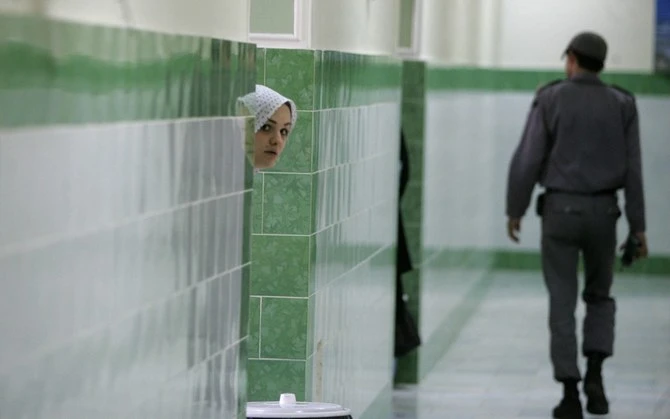In this 2006 file photo, an Iranian inmate peers from behind a wall as a guard walks by at the female section of the infamous Evin jail. (AFP)