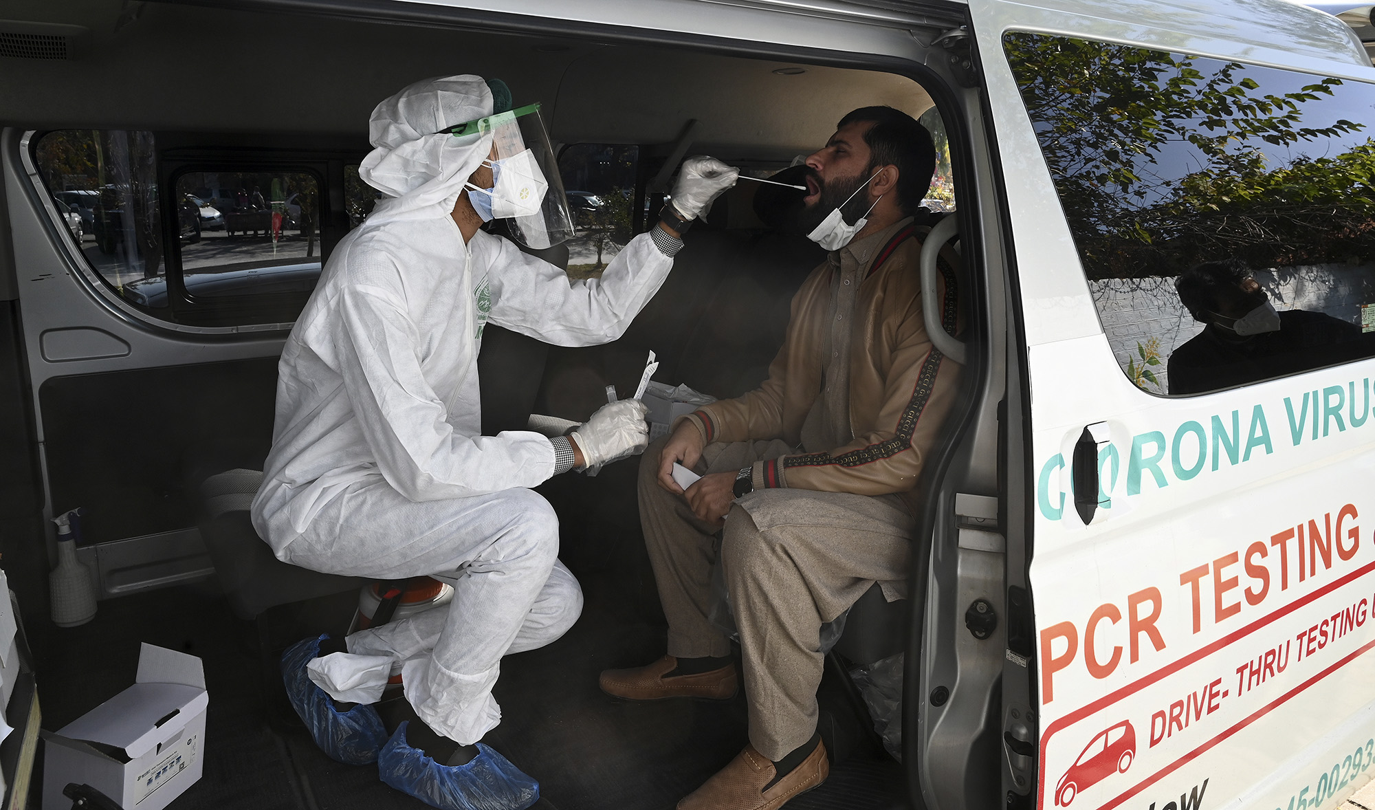 A health official collects a swab sample from a man to test for the Covid-19 coronavirus inside a van along the roadside in Islamabad on Nov. 26, 2020. (AFP/File)