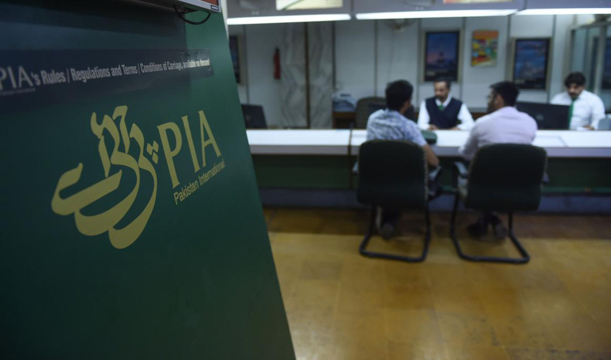 In this file photo, staff of Pakistan International Airlines (PIA) talk with passengers at a PIA office in Karachi on Feb. 27, 2019. (AFP)