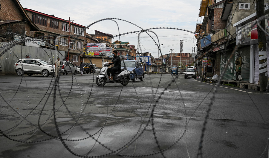 Motorists drive past a checkpoint with barbed fence wire in Srinagar on August 1, 2020. (AFP)