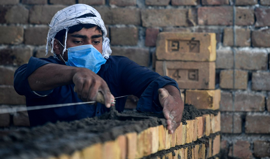 A worker wearing a facemask lays a brick wall at a construction site in Islamabad on May 6, 2020. (AFP/File)