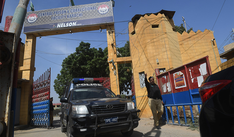 A Pakistani policeman gestures as a police vehicle leaves the Central Prison, where two men are held for starting a fire at a garment factory that killed over 260 people in 2012. (AFP)