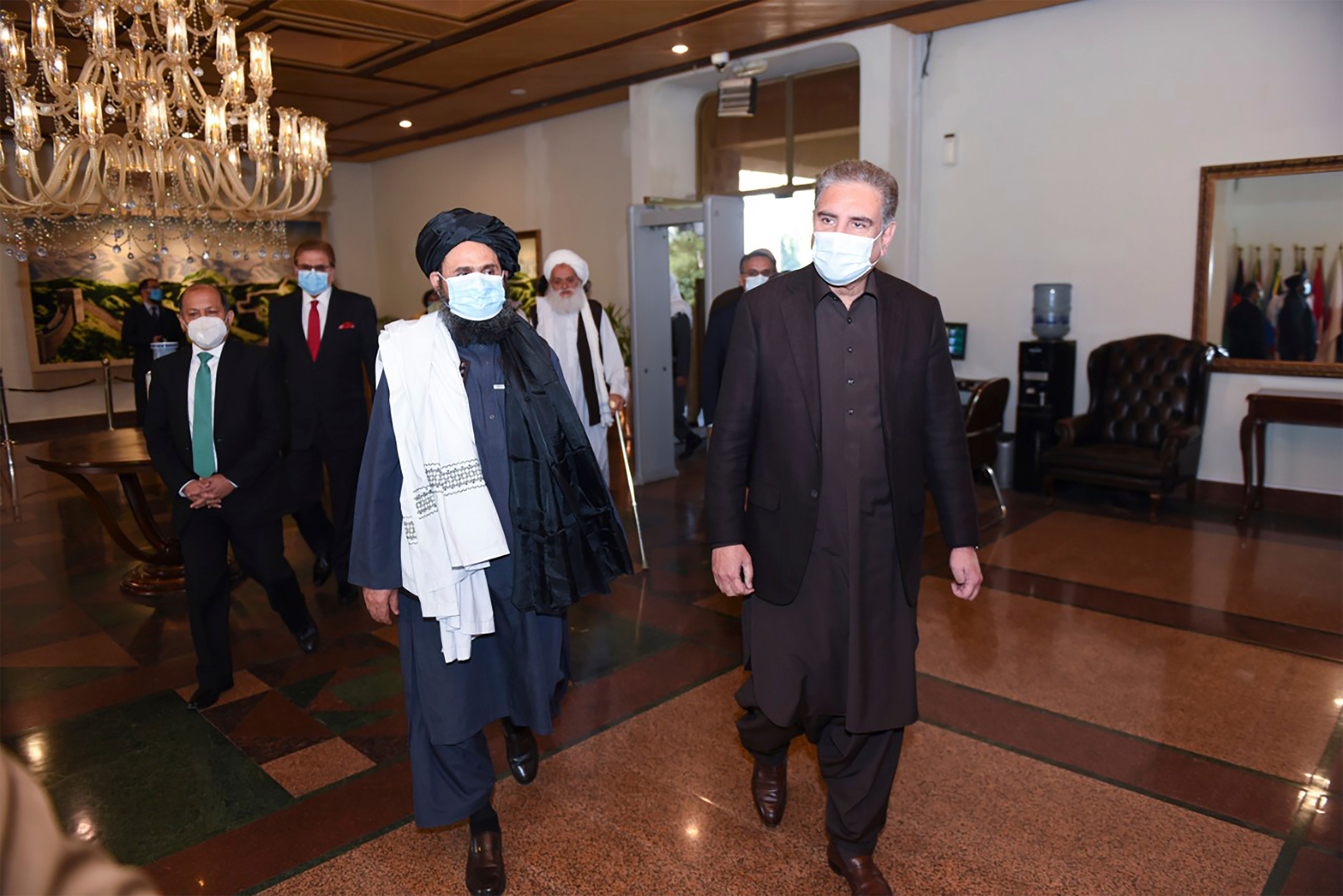 This handout photograph taken on December 16, 2020 and released by the Pakistan Foreign Ministry, shows Pakistan's Foreign Minister Shah Mehmood Qureshi (R) walking along with Taliban co-founder Mullah Abdul Ghani Baradar upon his arrival with the delegation for talks at the Pakistan Foreign Ministry in Islamabad. (AFP PHOTO/Pakistan Foreign Ministry)