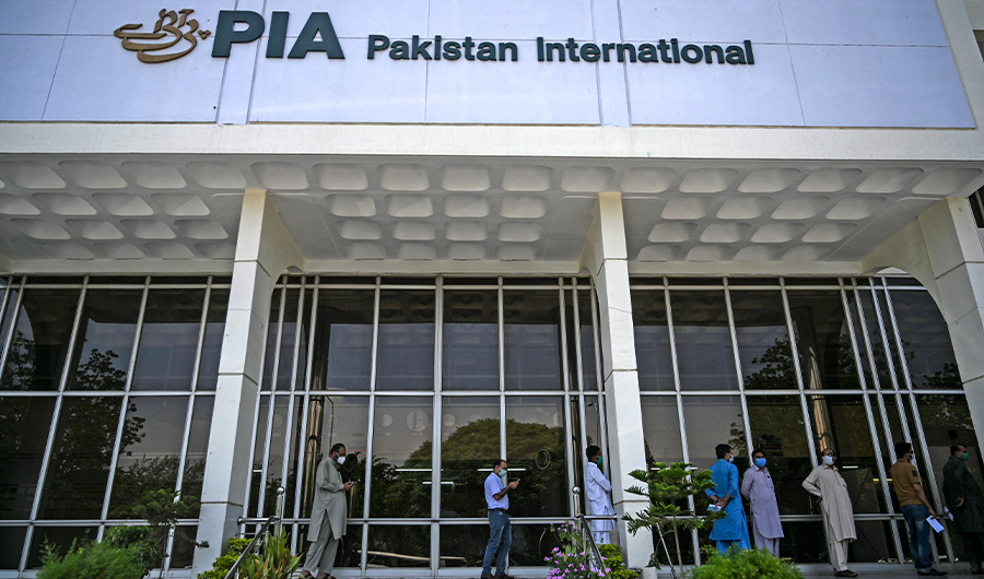 People stand in queue as they wait their turn to buy flight tickets outside Pakistan International Airlines (PIA) office in Islamabad on July 1, 2020 (AFP/File)
