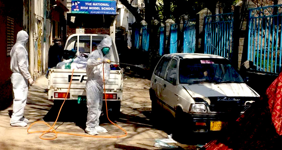 In this undated photo, health workers in Abbottabad spray chlorine water in a street after the death of a coronavirus patient was reported from the area. (APP)