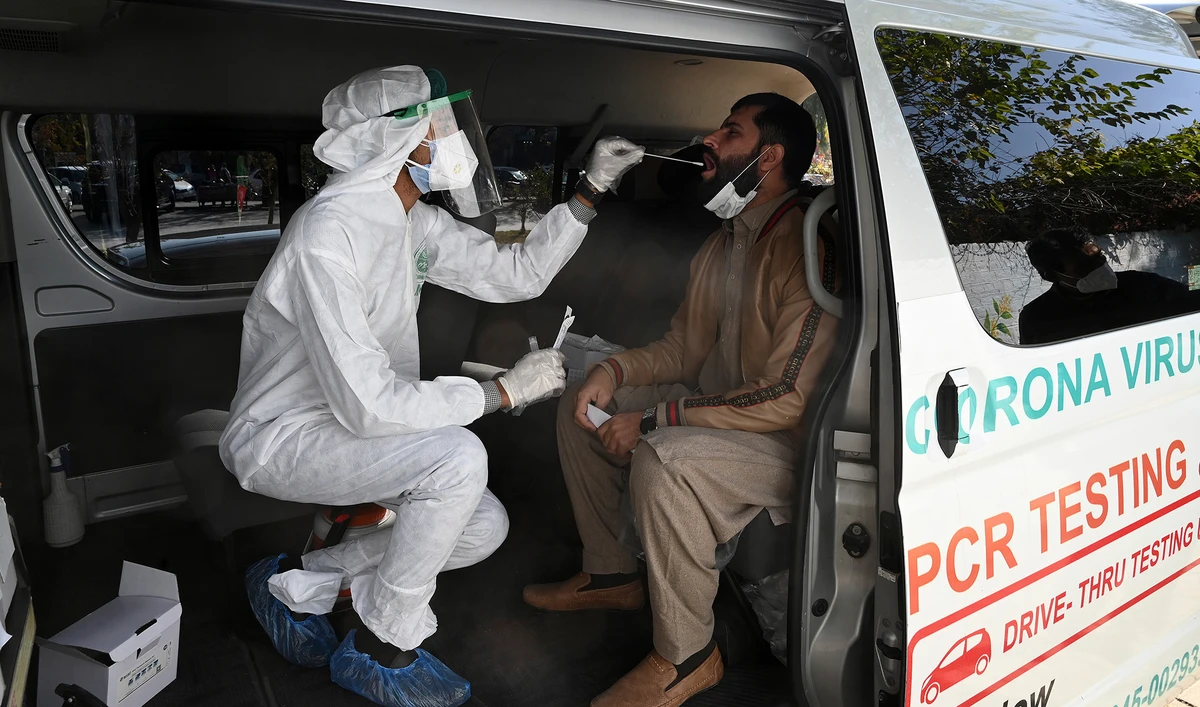 A health official collects a swab sample from a man to test for the Covid-19 coronavirus inside a van along the roadside in Islamabad on Nov. 26, 2020. (AFP/File)