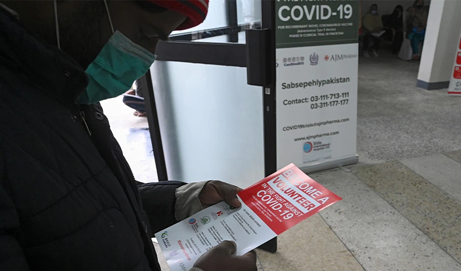In this picture taken on November 25, 2020 a volunteer reads an information leaflet while waiting to be administered the new Chinese-made vaccine for the Covid-19 coronavirus, the first ever Phase 3 clinical trial for any vaccine in Pakistan, at a hospital in Islamabad. (AFP)
