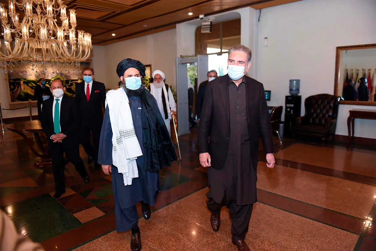 This handout photograph taken on December 16, 2020 and released by the Pakistan Foreign Ministry, shows Pakistan's Foreign Minister Shah Mehmood Qureshi (R) walking along with Taliban co-founder Mullah Abdul Ghani Baradar upon his arrival with the delegation for talks at the Pakistan Foreign Ministry in Islamabad. (AFP PHOTO/Pakistan Foreign Ministry)