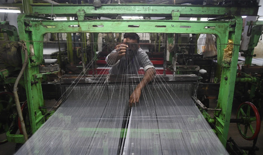 A Pakistan textile labourer fixes broken threads at a power loom in Karachi, on January 25, 2019, the financial capital and the largest industrial city of Pakistan. (AFP)