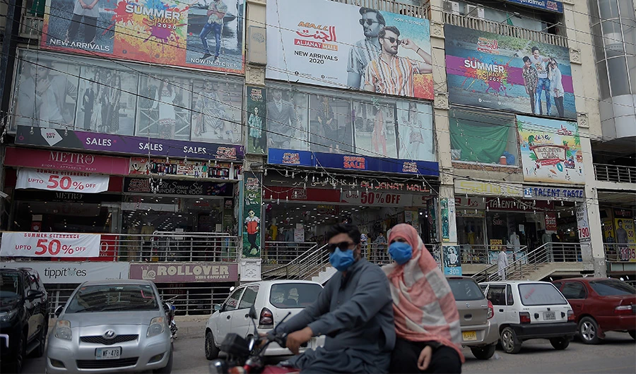 A family rides past a shoppig mall in Rawalpindi on July 28, 2020, after Punjab province government announced to closed markets, shopping malls and plazas to contain the spread of Covid-19 coronavirus on the occasion of the Muslim festival Eid al-Adha. (AFP)